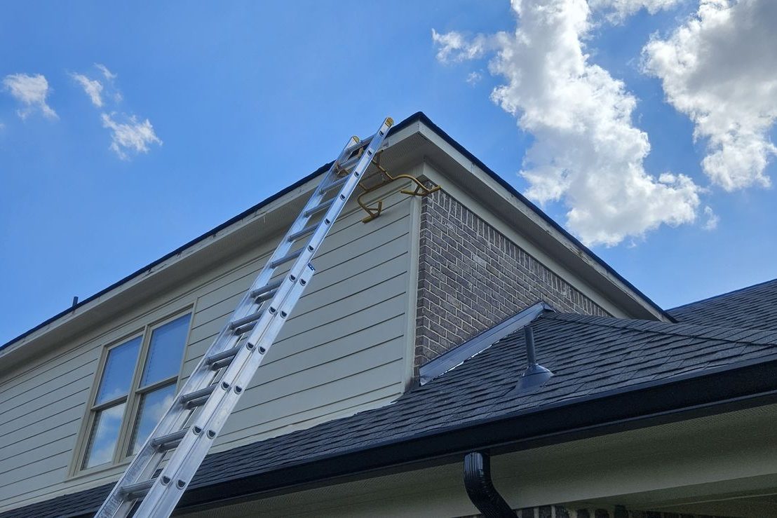 Ladder set against a two-story home for a gutter install