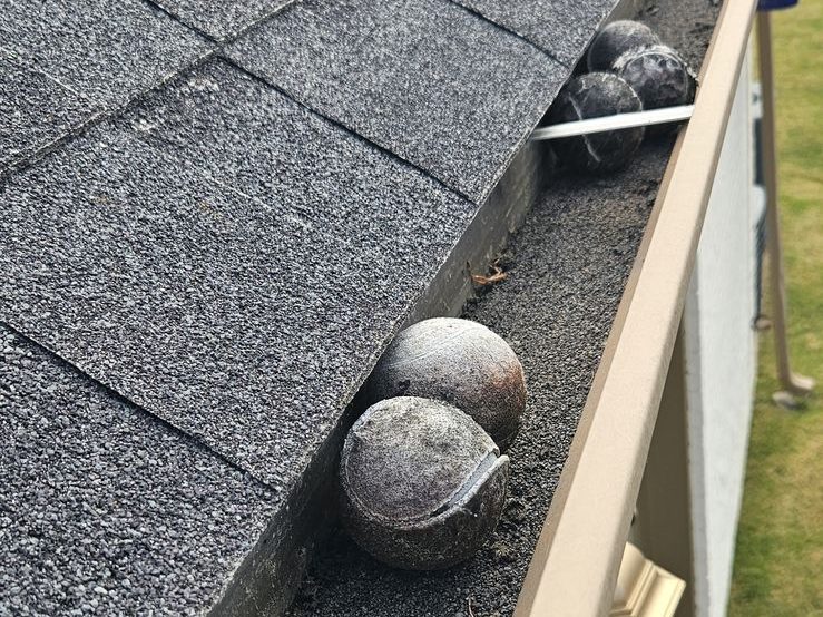 Tennis balls and shingle grit sitting in an open gutter