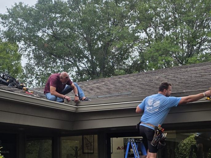 Two installers working the roofline of a commercial building